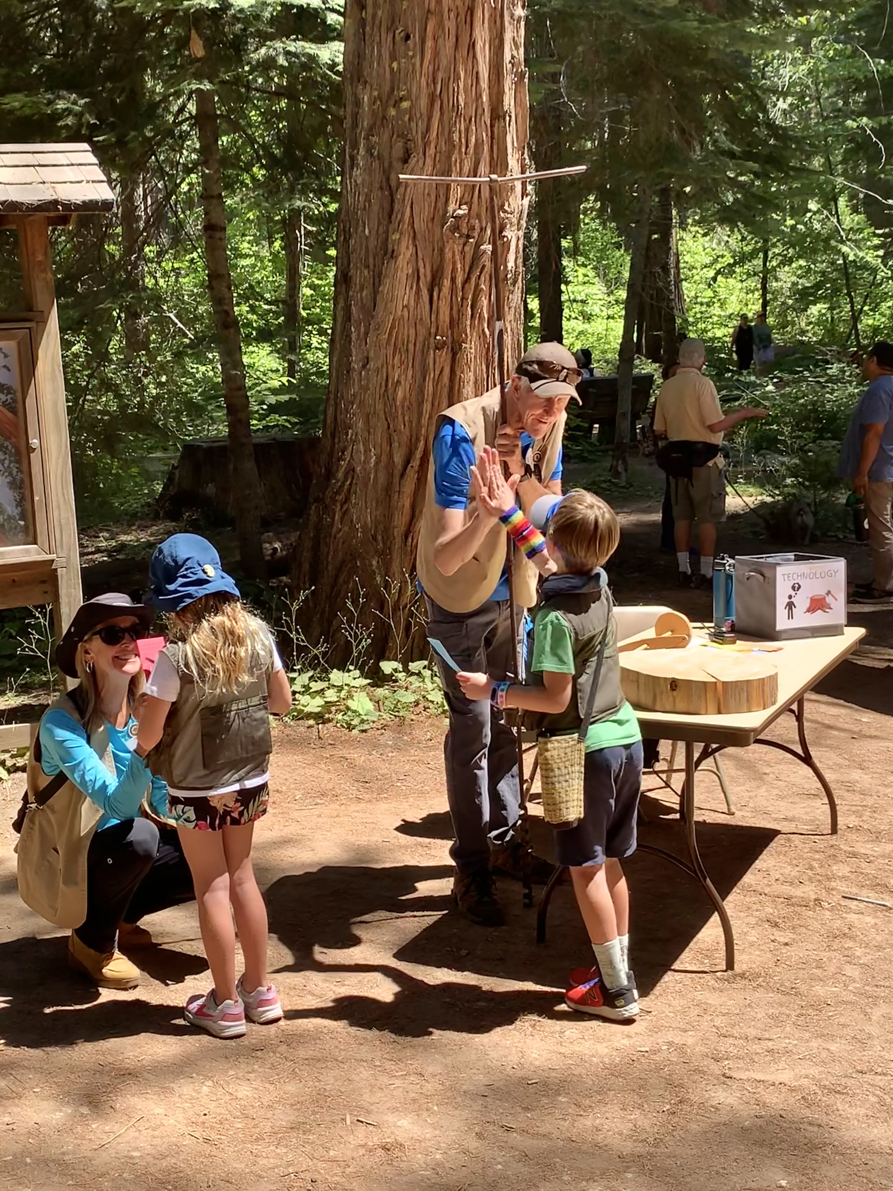 Two kids earn high-fives from volunteers from participating in a special event about engineering in the park. 